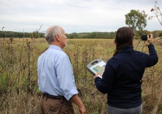 Quinte Conservation staff members standing with a landowner in an agricultural in late fall