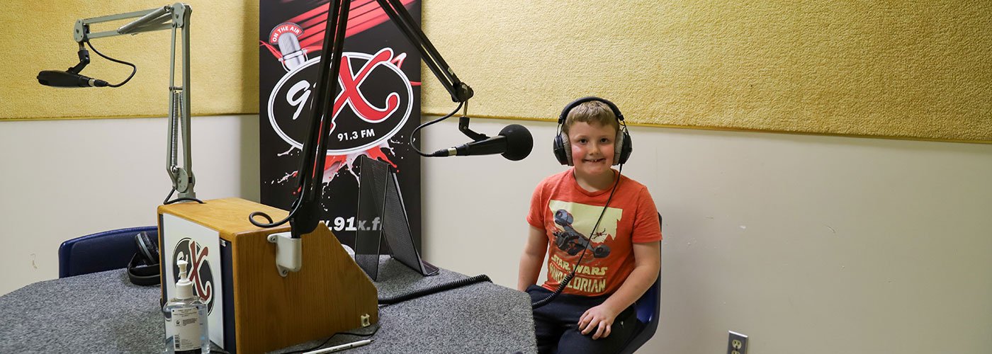 Alex Eveland, a Grade 3 student from St. Mary Catholic School, records his radio ad at his ad at Loyalist College’s 91X radio station.