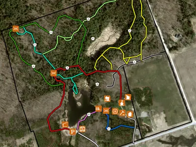 Aerial map showing various color-coded trails with symbols indicating different amenities and landmarks around a central lake.